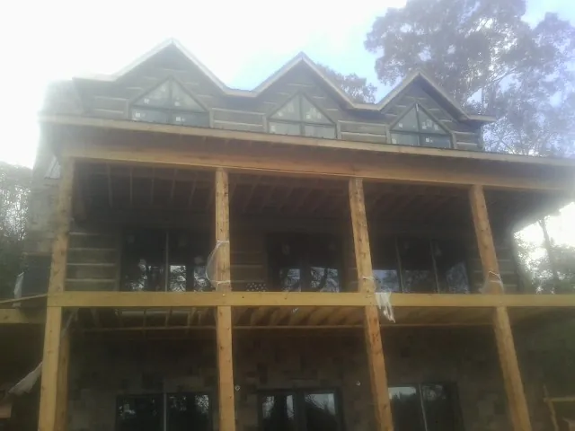 Dormers and porch framing on a large log home under construction — Roof Coating work by our crew in East Orleans