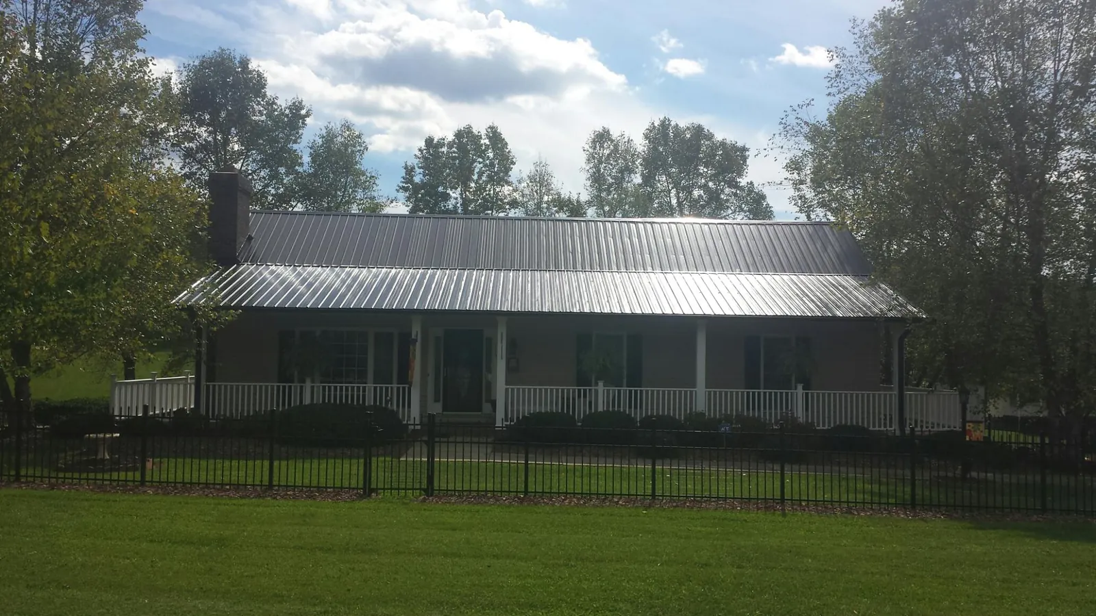 Gray metal roof on a brick ranch with a full width front porch — Gutter Guard Installation work by our crew in East Orleans