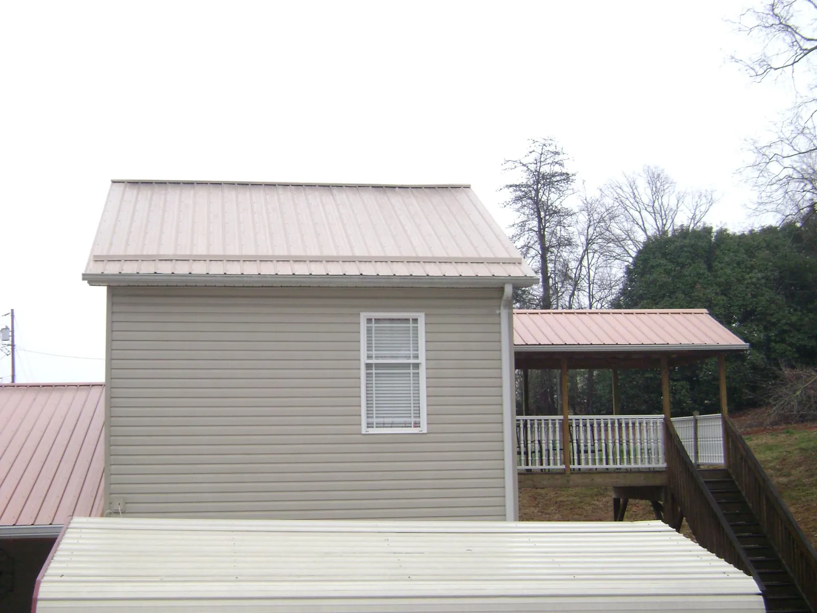 Tan metal roofs on a two story addition and attached porch, from a Roof Replacement job in East Orleans